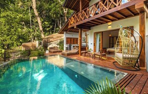Relax by the serene pool surrounded by lush greenery and a wooden deck.
