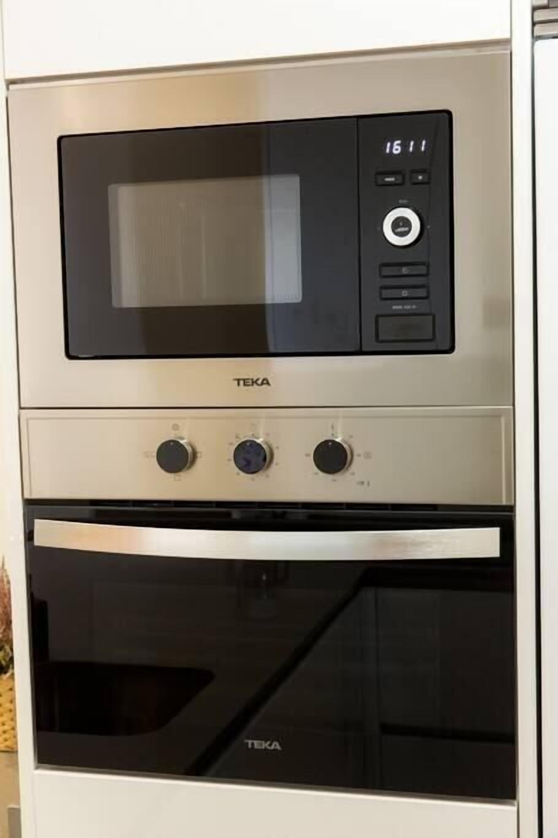 Una cocina con microondas y horno, ambos de la marca TEKA.
