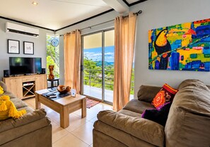 A modern living room with a television, sofa, coffee table, and artwork.