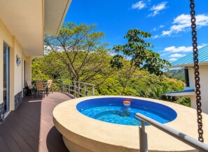 A hot tub on a deck with a view of a lush green landscape.