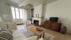 A living room with a sofa, a coffee table, a fireplace, a television, and a bookshelf.