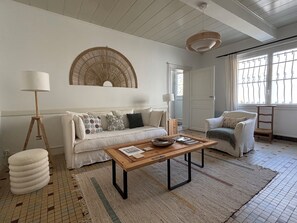 A living room with a sofa, a coffee table, a floor lamp, and a chair. - Située au Coeur des Vignobles du Médoc, Près de Bordeaux et des Plages Océanes (Saint-Estèphe)