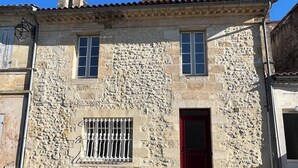 A stone building with a red door, a small window with bars, and a chimney.