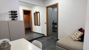 Een moderne, minimalistische woonkamer met een witte tafel, een bank en een decoratieve vaas.