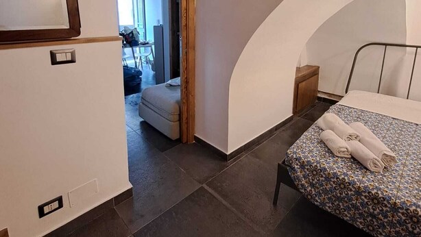 Een slaapkamer met een bed, een klein nachtkastje en een raam.