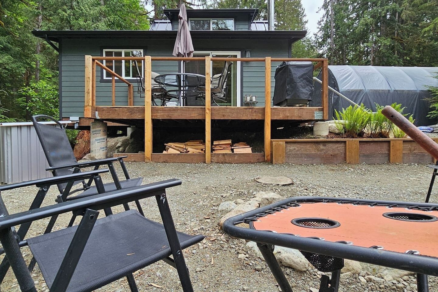 Een achtertuin met een terras, buitenmeubels en een overdekte barbecueplek.