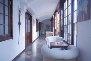A hallway with a bench, a table, and a large window. - Xianting Inn (Liyang)