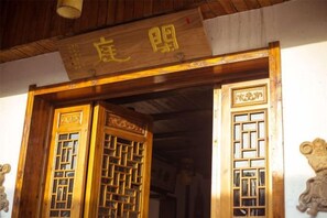 A traditional wooden door with intricate lattice patterns and a sign above it. - Xianting Inn (Liyang)