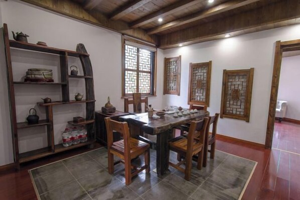 A traditional dining room with a wooden table and chairs, a bookshelf, and decorative screens.
