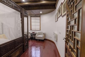 A bedroom with a four-poster bed, a small table, and a chair.