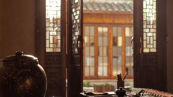 A traditional room with a large ceramic pot, a wooden table, and a view through a wooden door with glass panels.