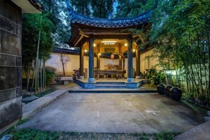 A traditional Japanese-style pavilion with a stone pathway leading to it, surrounded by bamboo plants.
