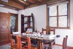 A traditional dining room with a wooden table set for tea, surrounded by chairs. - Xianting Inn (Liyang)