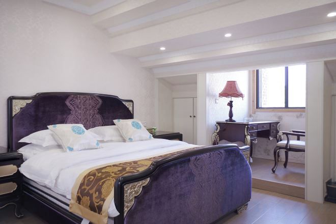 A bedroom with a large bed, bedside tables, a desk, and a chair.