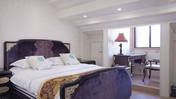 A bedroom with a large bed, bedside tables, a desk, and a chair.