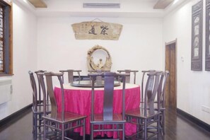 A dining area with a round table, chairs, and a pink tablecloth. - Xianting Inn (Liyang)