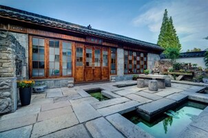 Un edificio tradicional con un patio, escalones de piedra y una pequeña fuente.