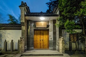 Fachada de edificio tradicional con puerta de madera, pilares de piedra y techo de tejas.