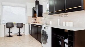 Una cucina moderna con mobili neri, una lavatrice integrata e due sgabelli da bar.