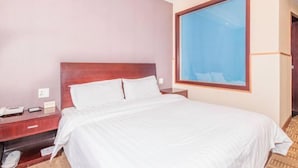 A hotel room with a large bed, a wooden headboard, a nightstand, and a window with a view. - Yindu Hotel (Pinghu)