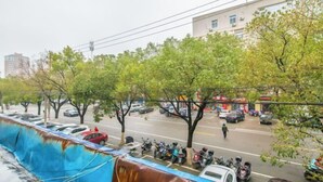 A street view with parked cars, trees, and a building in the background. - Yindu Hotel (Pinghu)