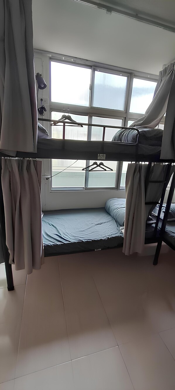 A bunk bed room with a window, curtains, and a hanging rack.