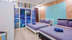 A modern hotel room with two beds, a large sliding glass door leading to a balcony, and a brick accent wall. - Baan Bonhuer Pool Villa Hua-Hin (Hua Hin)