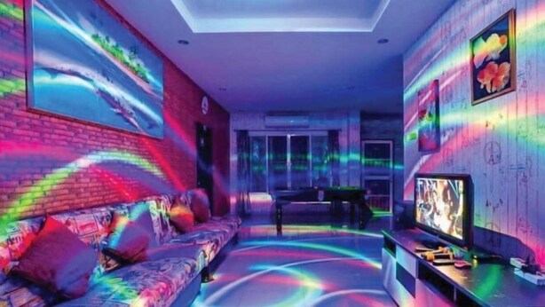 A room with a sofa, a television, and a wall with a colorful light display. - Baan Bonhuer Pool Villa Hua-Hin (Hua Hin)