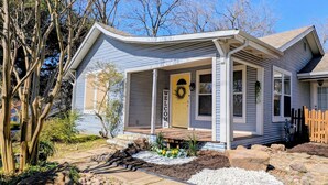 Une maison avec une porte d’entrée accueillante, un porche abrité et un jardin bien entretenu agrémenté de rochers et de plantes.