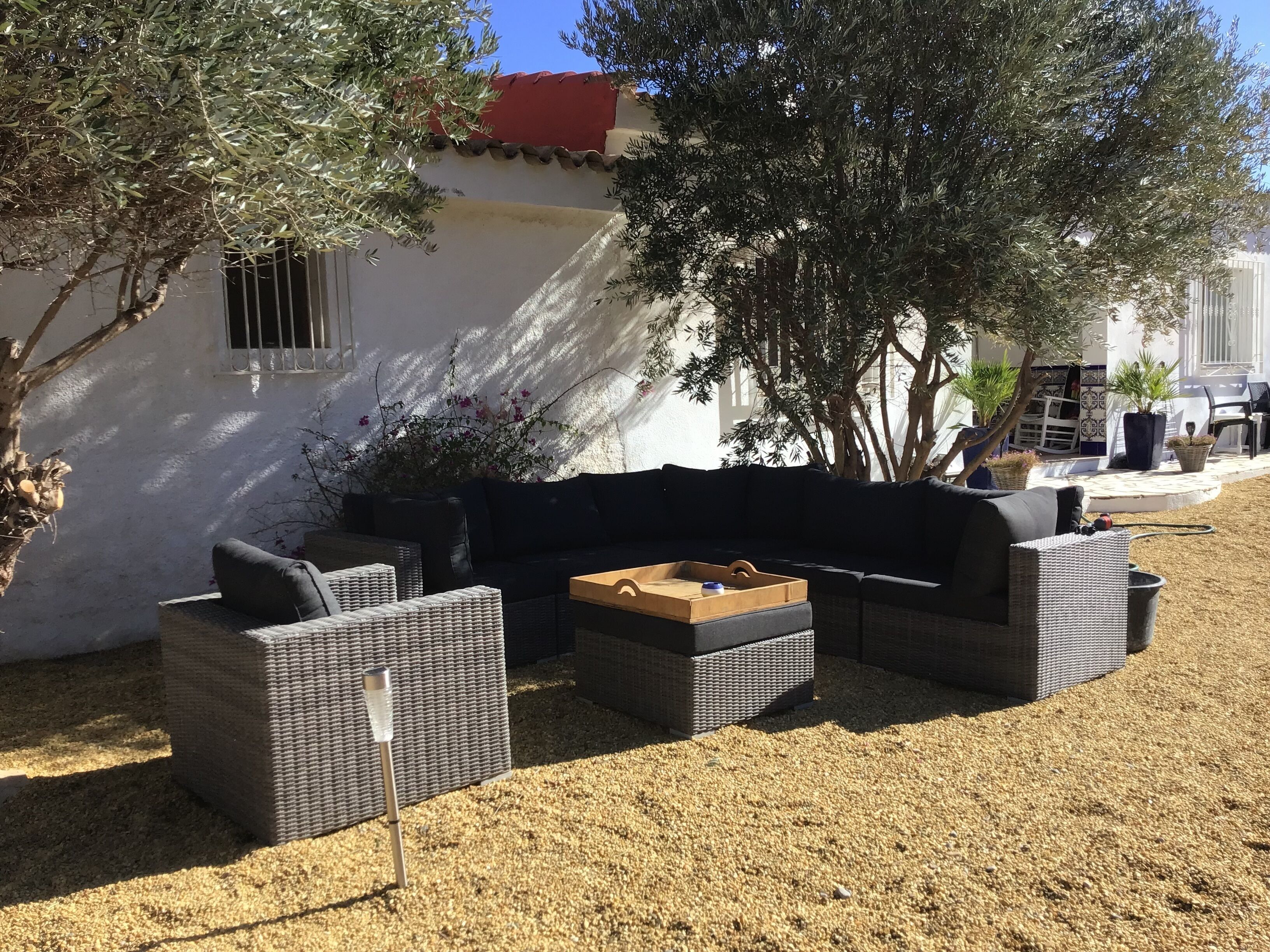 Un área de estar al aire libre con muebles de mimbre, una mesa pequeña y una planta en maceta.