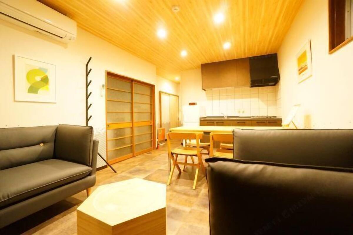 A modern living room with a sofa, a coffee table, and a dining area with chairs.