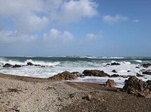 Una costa rocciosa con le onde che si infrangono sulle rocce sotto un cielo sereno.