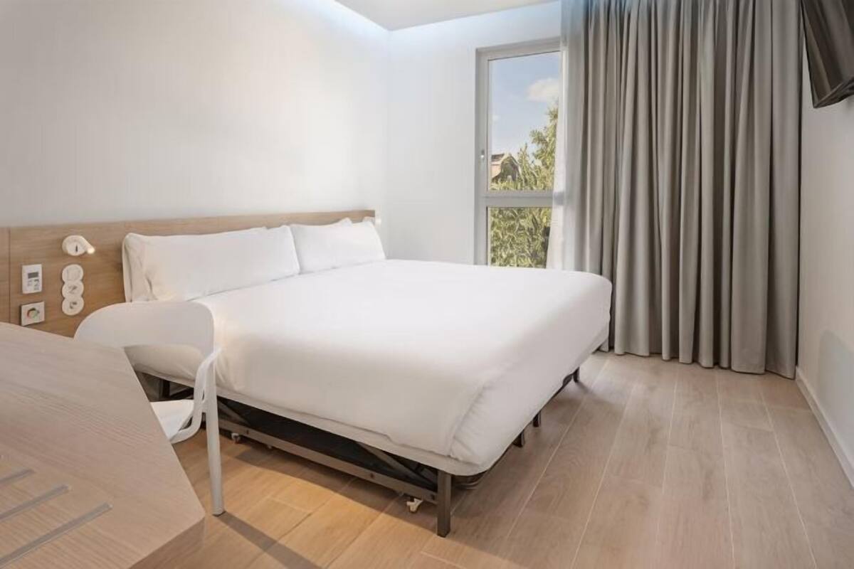Une chambre à coucher avec un lit, un bureau et une fenêtre avec des rideaux.