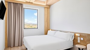 A bedroom with a bed, a window with a view, a TV, and a small table. - B&B Hotel Madrid Tres Cantos  (Tres Cantos)