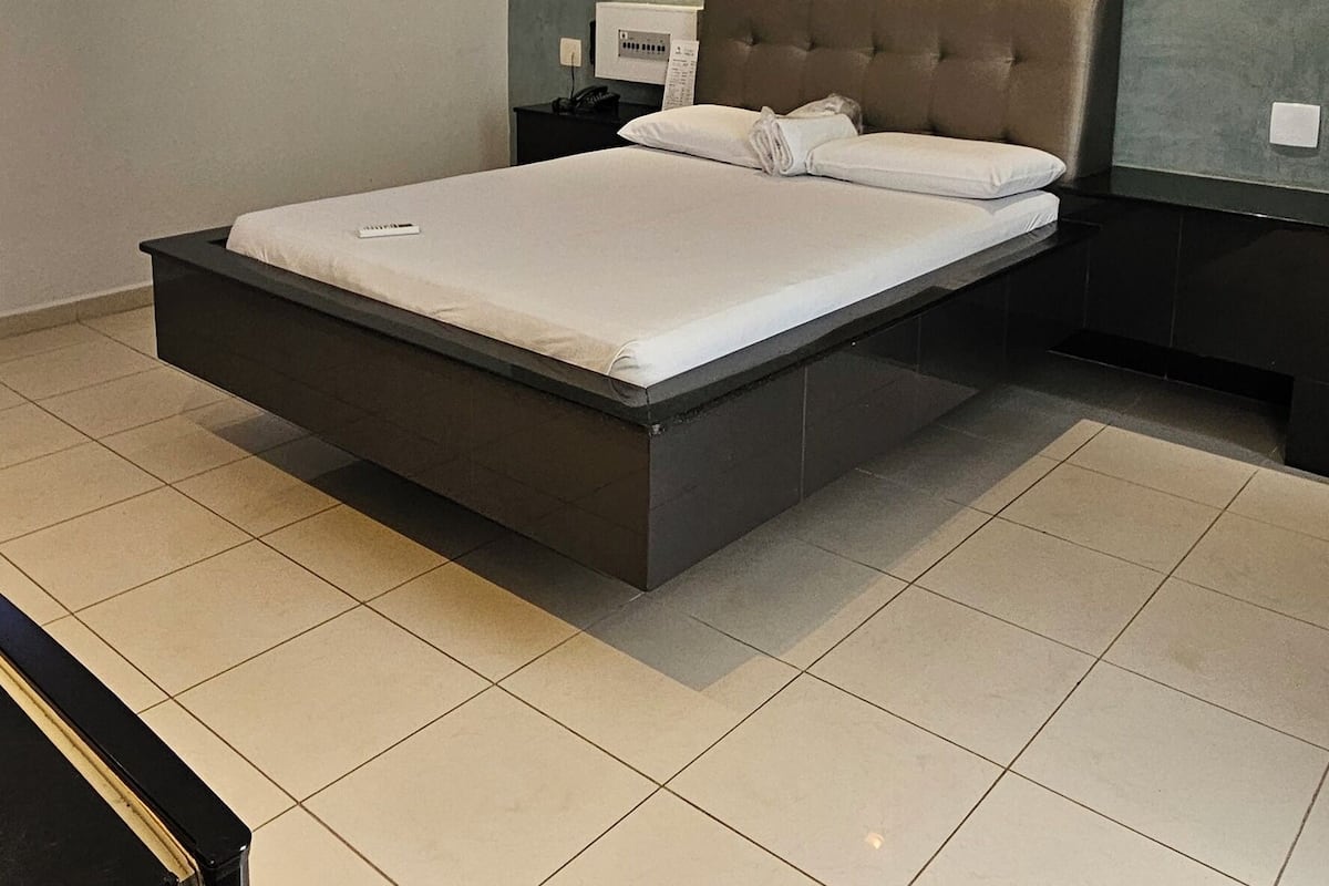 Ein modernes Schlafzimmer mit einem großen Bett, einem Nachttisch, einer Klimaanlage und einer Wandleuchte.