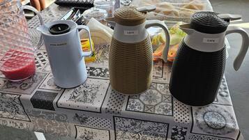 A table with a variety of kitchenware including a blender, a white mug, and two insulated water bottles.