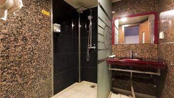 Ein Badezimmer mit Dusche, Waschbecken mit roter Ablage und Spiegel mit rotem Rahmen.