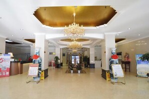 A hotel lobby with a chandelier, reception desk, and informational signs. - Zhongyuan Dasha Business Hotel (Zhengzhou)