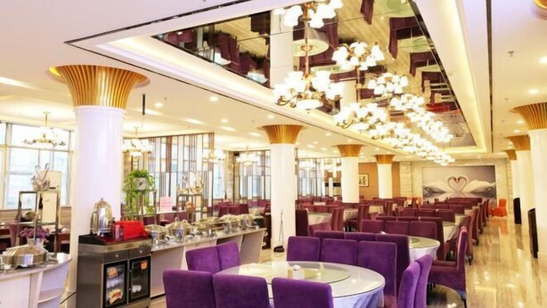 A modern dining area with purple upholstered chairs, a central bar area, and contemporary lighting fixtures. - Zhongyuan Dasha Business Hotel (Zhengzhou)