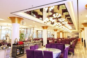 A modern dining area with purple upholstered chairs, a central bar area, and contemporary lighting fixtures. - Zhongyuan Dasha Business Hotel (Zhengzhou)