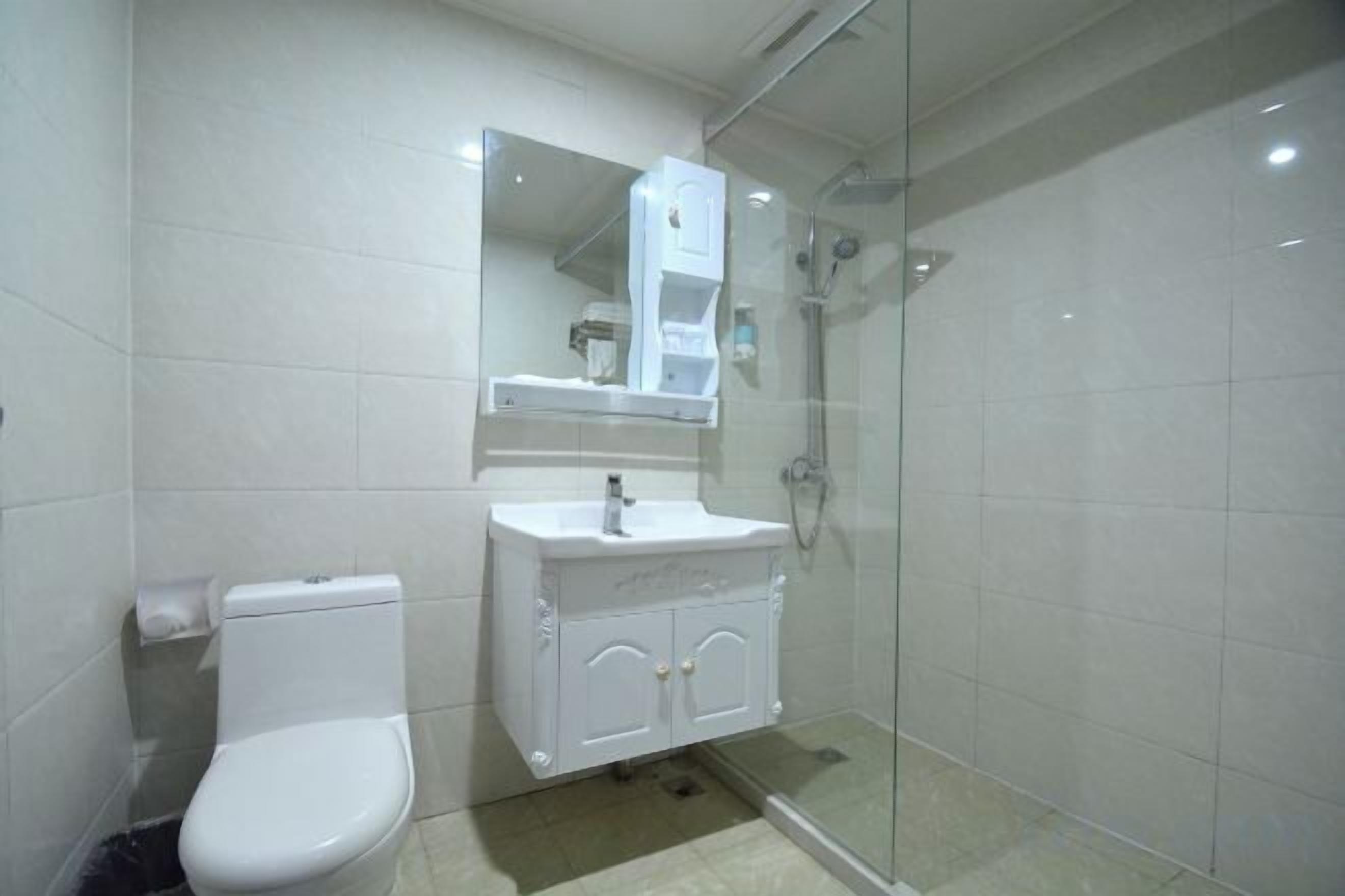 A bathroom with a toilet, sink, and glass shower enclosure.
