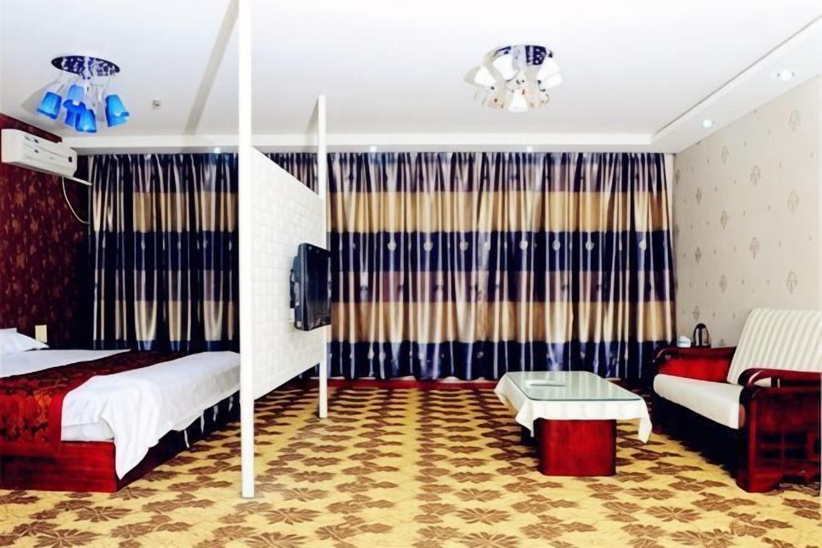 Una habitación de hotel con una cama, un sofá, un televisor y una alfombra estampada.