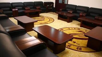 A conference room with black leather sofas, wooden tables, and a patterned carpet.
