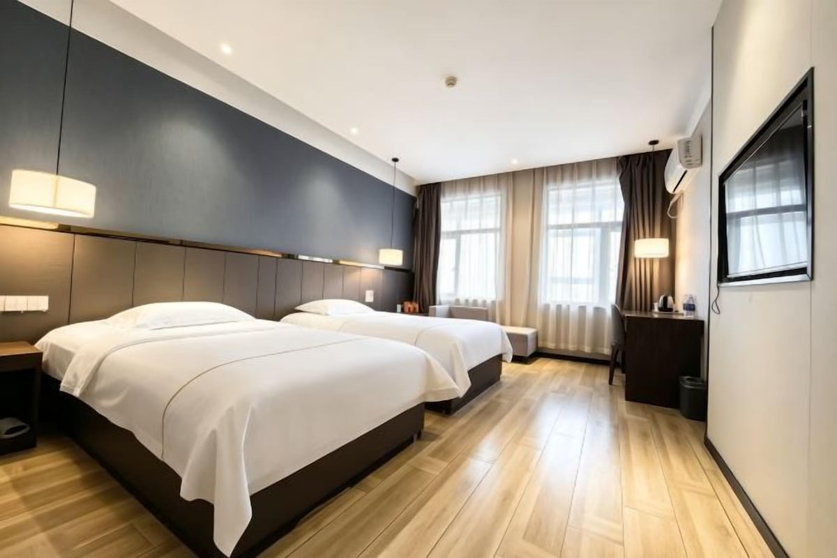 Ein Hotelzimmer mit zwei Betten, einem Schreibtisch und einem großen Fenster.