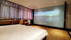 A hotel room with a large bed, a desk with a chair, a large screen displaying a scenic view, and a wardrobe. - Zhongyuan Dasha Business Hotel (Zhengzhou)