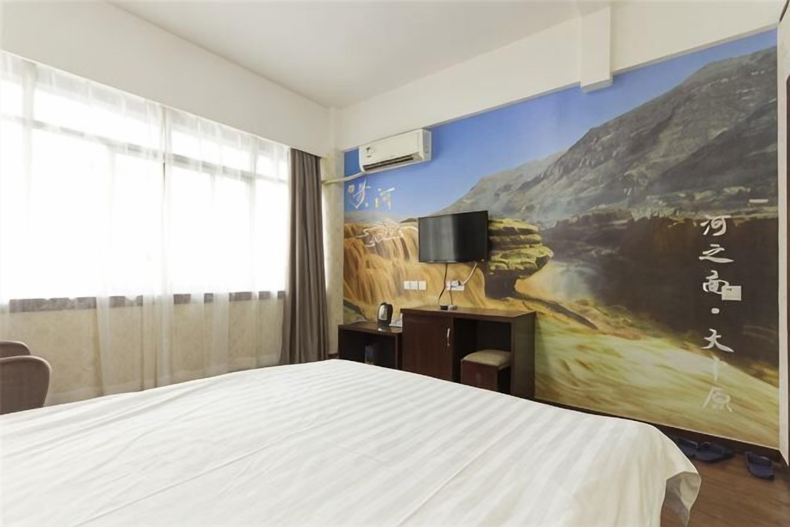 Una habitación de hotel con una cama, un escritorio con silla, un televisor y un mural grande en la pared.