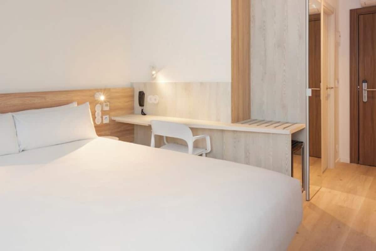 Una habitación de hotel con una cama grande, un escritorio y una silla.