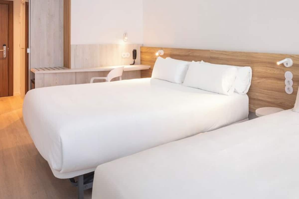 Una habitación de hotel con dos camas, un escritorio y una silla.