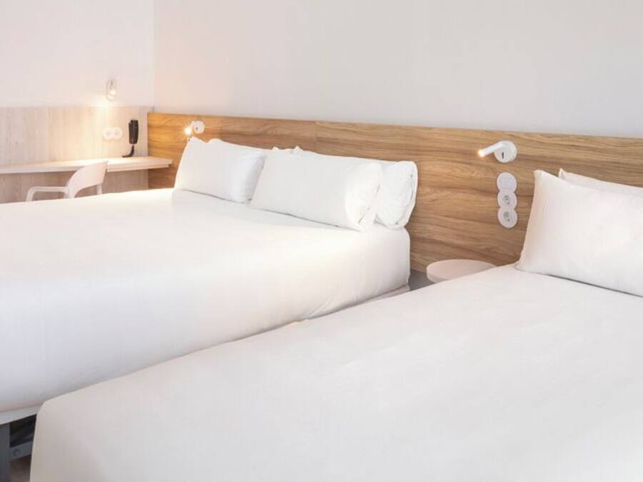 A hotel room with two beds, a desk, and a chair.