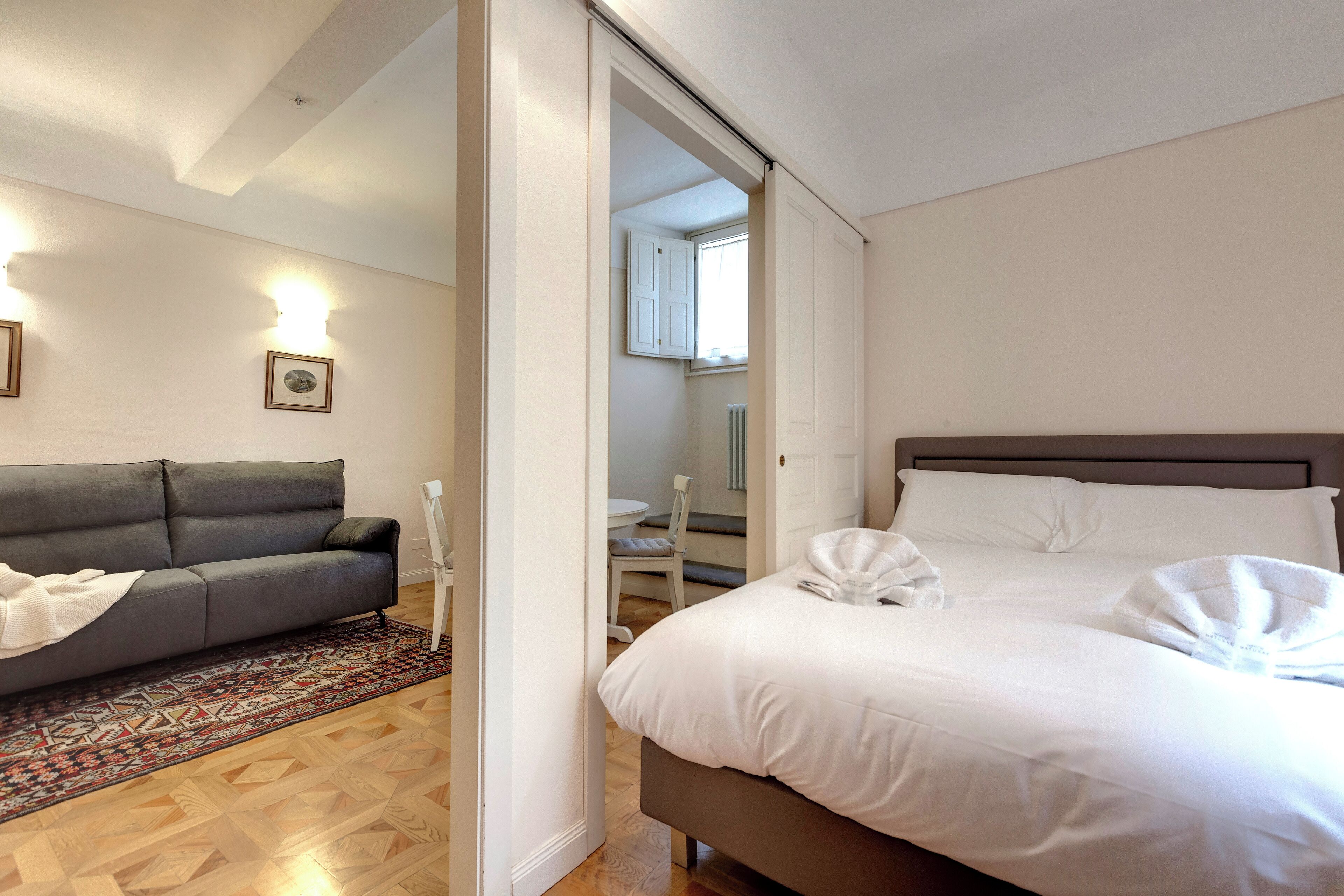 A bedroom with a bed, a sofa, and a small table.